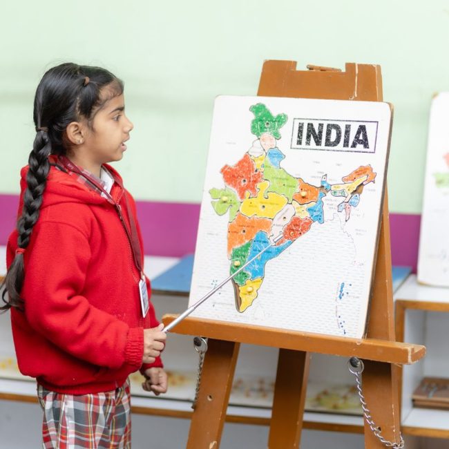 Young student points to India map in a classroom, fostering education.